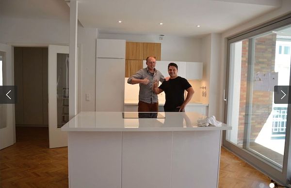 Zufriedener Kunde mit Küchenmonteur — weiße Küche mit Kochinsel