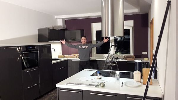 Fertige schwarze Küche mit Kochinsel — stolzer Monteur