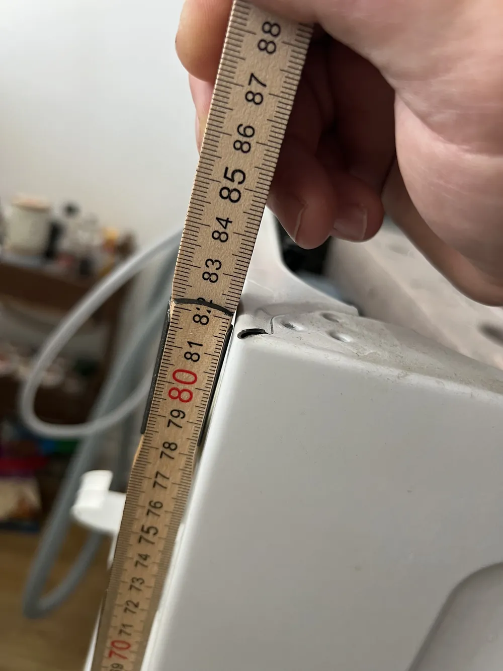 Zollstock an der Oberkante der Waschmaschine ohne Deckel, die Kante liegt bei 82 Zentimetern