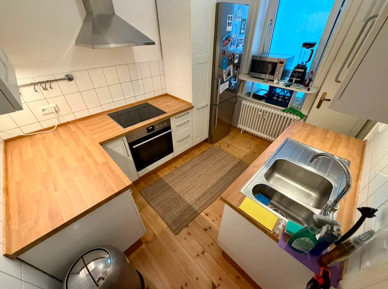 Fertige Hamburger Küche nach dem Arbeitsplattenwechsel von oben fotografiert: helle Eiche-Arbeitsplatte über beide Zeilen, links Kochfeld und Backofen, rechts die Spüle, dazwischen der Dielenboden.